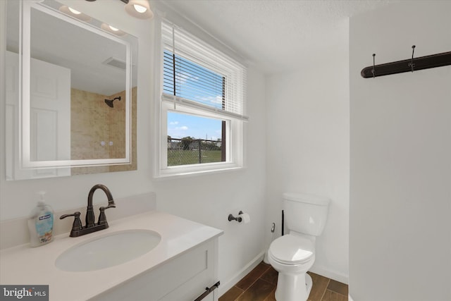 bathroom featuring a tile shower, a textured ceiling, vanity, hardwood / wood-style flooring, and toilet