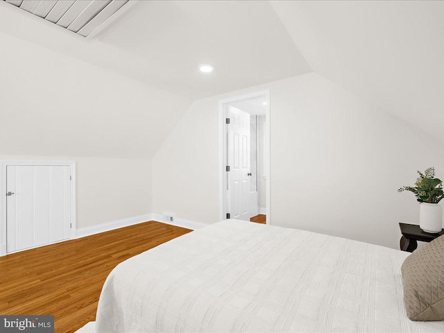 bedroom featuring hardwood / wood-style flooring, lofted ceiling, and ensuite bathroom