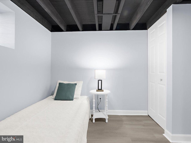 bedroom featuring hardwood / wood-style floors and beamed ceiling