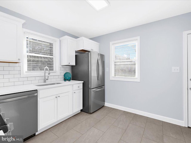 kitchen with decorative backsplash, appliances with stainless steel finishes, sink, white cabinetry, and light tile patterned flooring