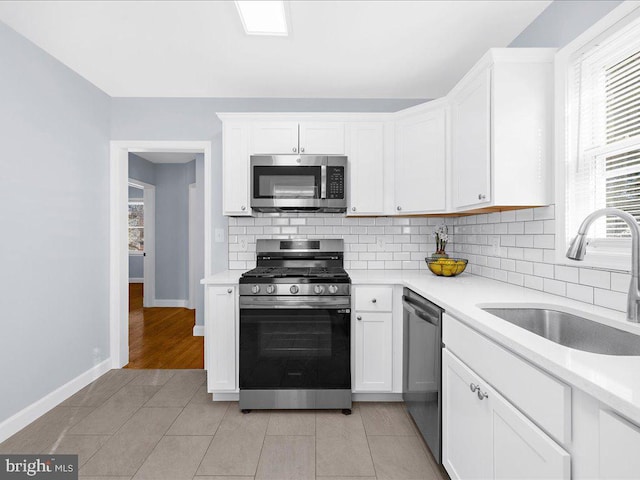 kitchen with white cabinetry, sink, tasteful backsplash, light hardwood / wood-style flooring, and appliances with stainless steel finishes