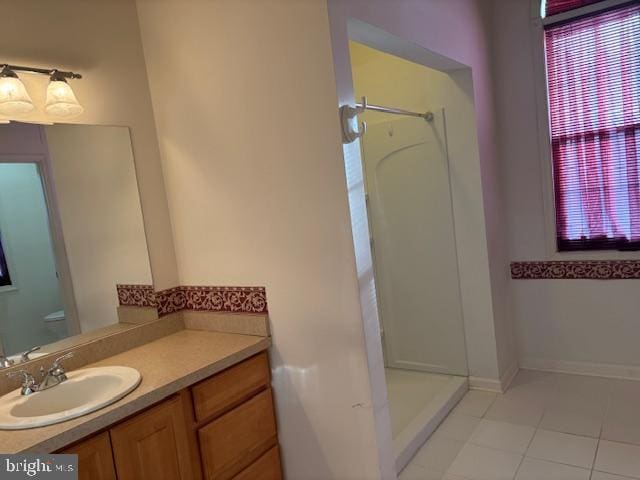 bathroom featuring tile patterned flooring, vanity, toilet, and a shower