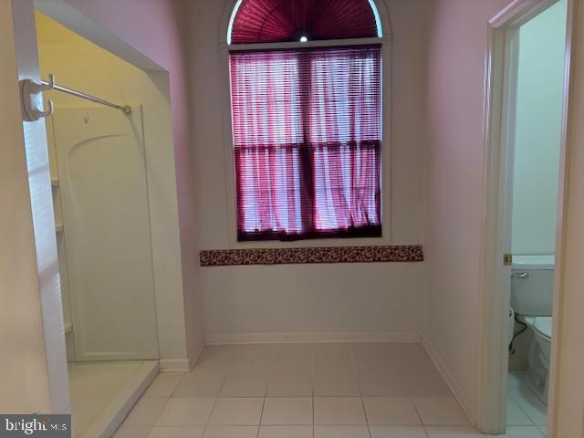 bathroom featuring a shower, tile patterned flooring, and toilet