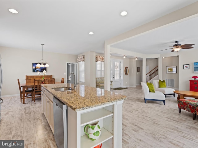 kitchen featuring dishwasher, sink, light hardwood / wood-style flooring, an island with sink, and light stone counters