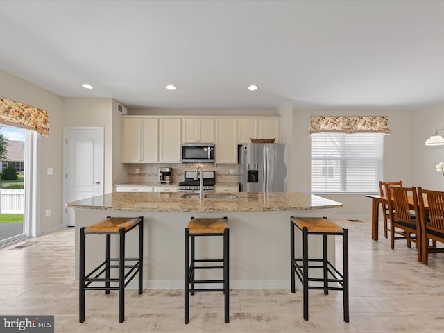 kitchen with a kitchen bar, appliances with stainless steel finishes, a center island with sink, and sink