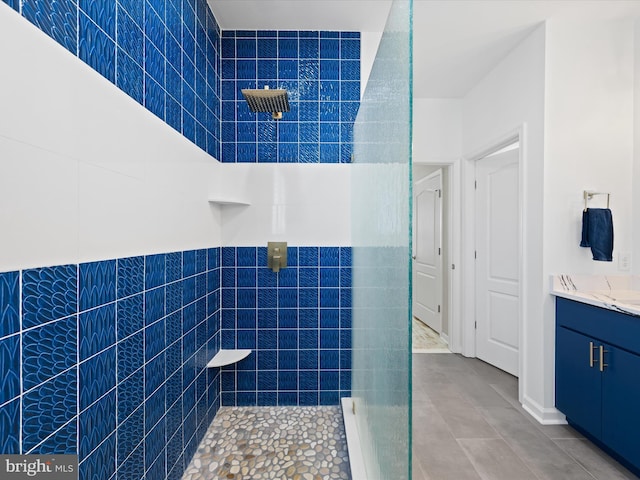 bathroom with tile patterned floors, vanity, tile walls, and tiled shower