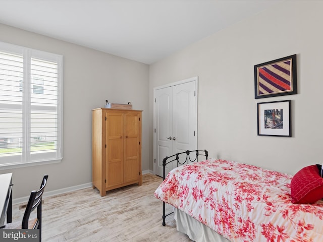 bedroom featuring light hardwood / wood-style floors, a closet, and multiple windows