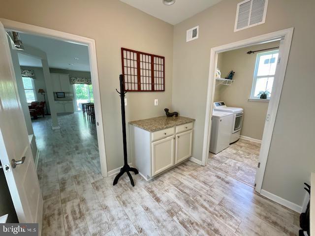 clothes washing area with independent washer and dryer and light hardwood / wood-style flooring