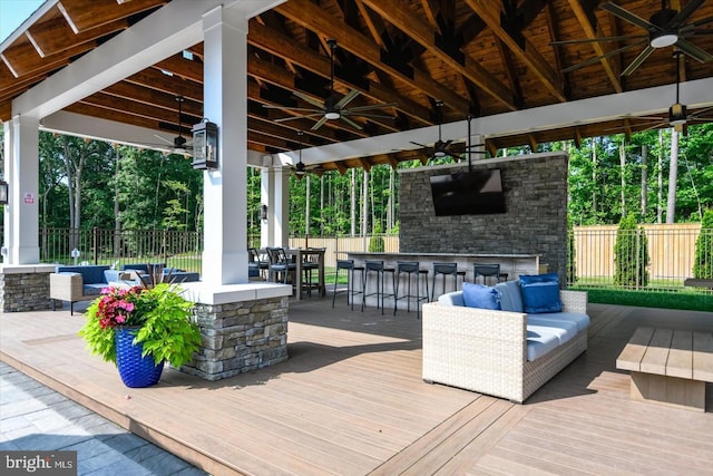 wooden terrace with ceiling fan, an outdoor bar, and an outdoor living space