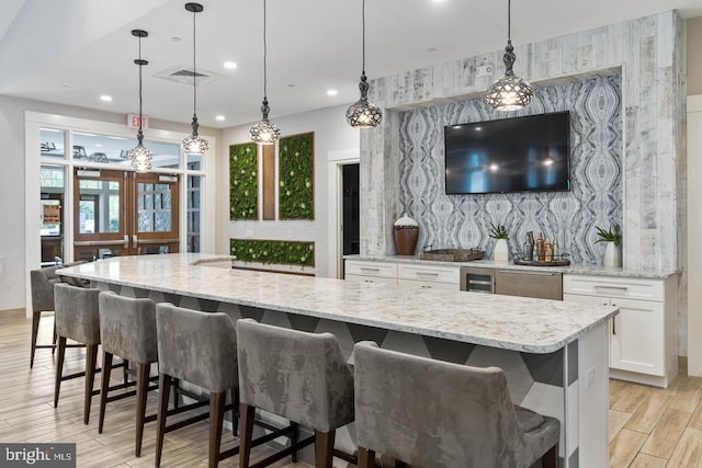 kitchen with a kitchen breakfast bar, light wood-type flooring, decorative light fixtures, and white cabinetry