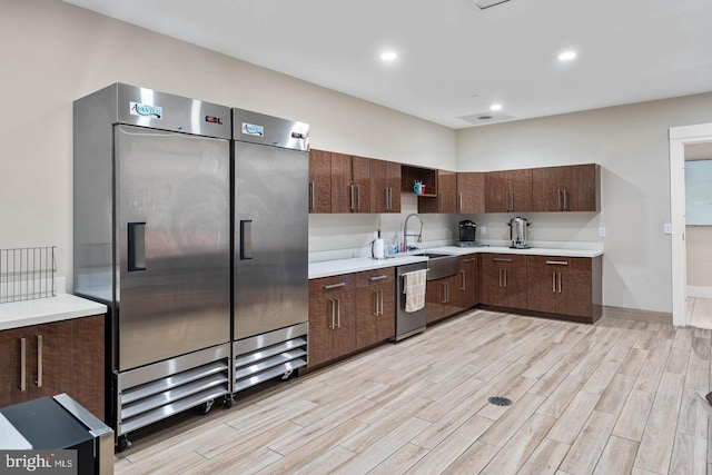 kitchen featuring sink, dark brown cabinetry, stainless steel appliances, and light hardwood / wood-style flooring