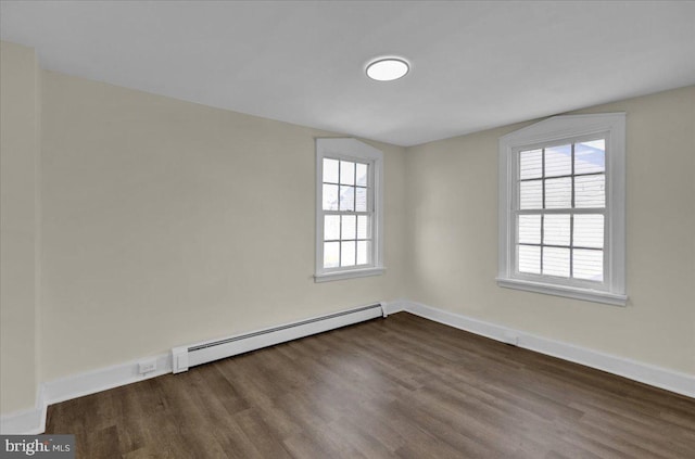 spare room featuring baseboard heating and dark wood-type flooring