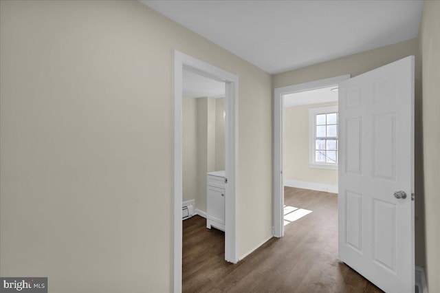 hall with dark hardwood / wood-style flooring and a baseboard heating unit