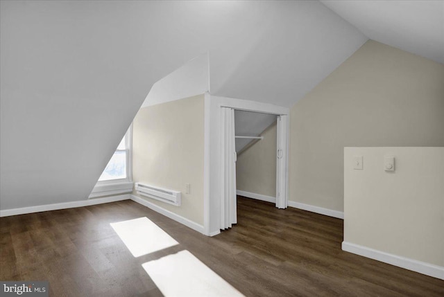 additional living space featuring dark wood-type flooring, baseboard heating, and vaulted ceiling