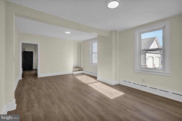 empty room with a baseboard radiator and dark hardwood / wood-style floors