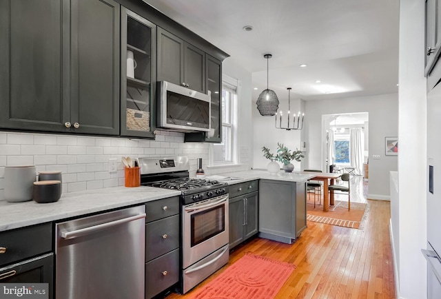 kitchen featuring hanging light fixtures, appliances with stainless steel finishes, light wood-type flooring, and a wealth of natural light