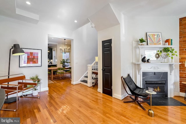 living area with a chandelier, wood-type flooring, and a premium fireplace