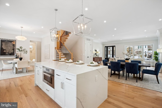 kitchen featuring white cabinets, decorative light fixtures, light stone counters, and a kitchen island