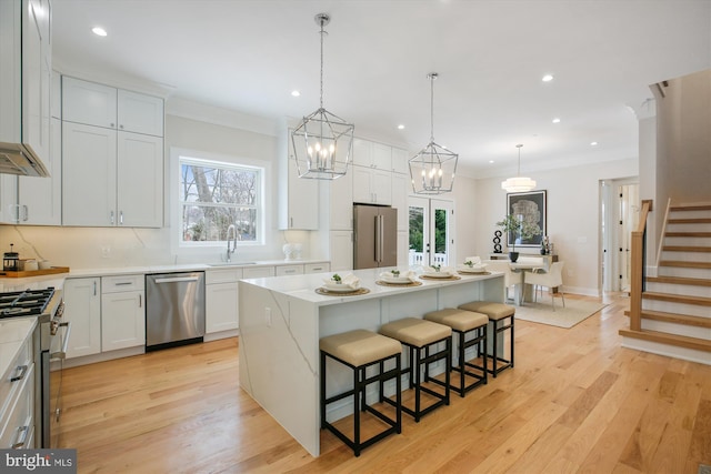 kitchen featuring pendant lighting, a center island, premium appliances, white cabinetry, and sink