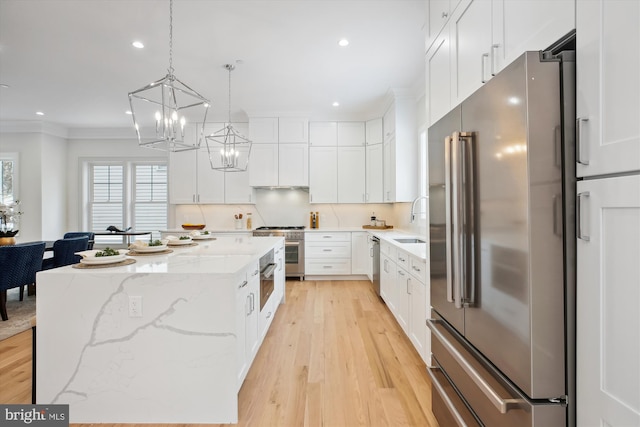 kitchen with decorative light fixtures, white cabinets, high end appliances, and a center island