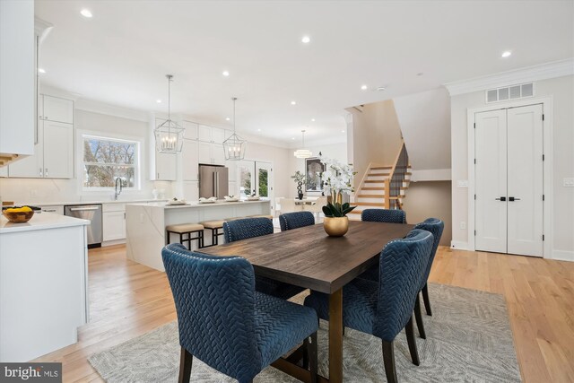 dining space with light hardwood / wood-style floors, crown molding, and sink