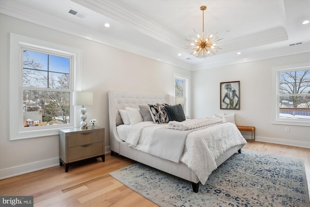 bedroom with a raised ceiling, a chandelier, light hardwood / wood-style floors, and ornamental molding