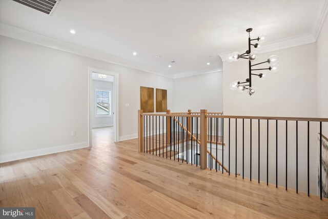 hall with light wood-type flooring, a notable chandelier, and crown molding