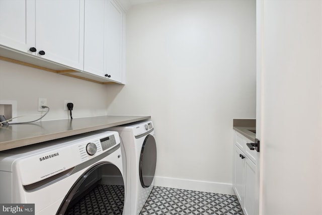 clothes washing area with washer and dryer and cabinets