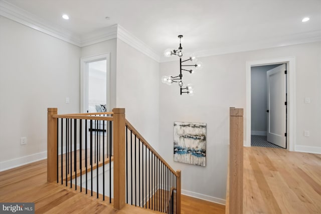 stairway featuring an inviting chandelier, ornamental molding, and hardwood / wood-style floors