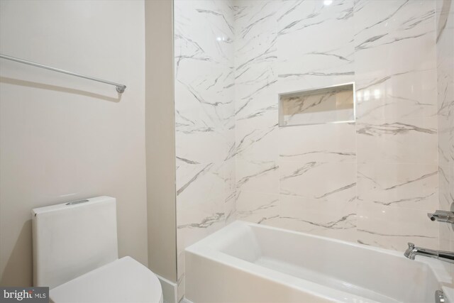 bathroom featuring tiled shower / bath combo and toilet