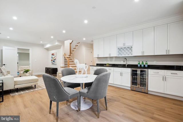 dining room featuring sink, light wood-type flooring, and wine cooler