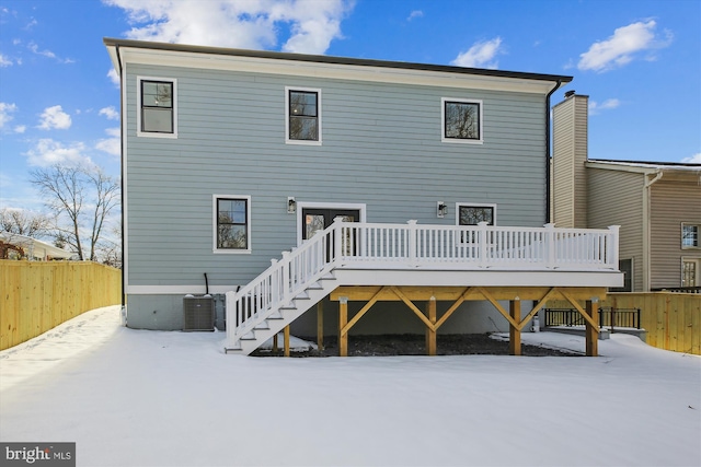 snow covered rear of property with a deck and central AC