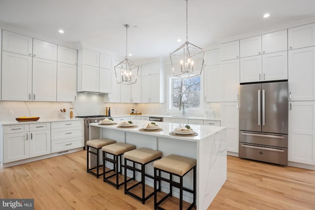 kitchen featuring white cabinets, a breakfast bar area, hanging light fixtures, a kitchen island, and appliances with stainless steel finishes