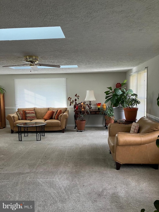 carpeted living room featuring a skylight, ceiling fan, and a textured ceiling