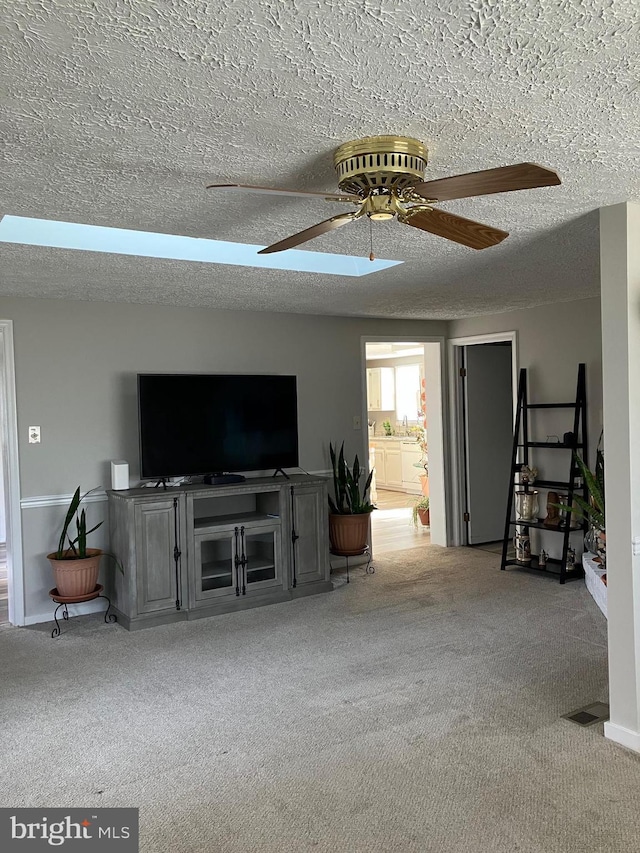 living room with ceiling fan, light colored carpet, and a textured ceiling