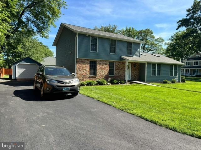 front facade featuring an outbuilding, a front yard, and a garage