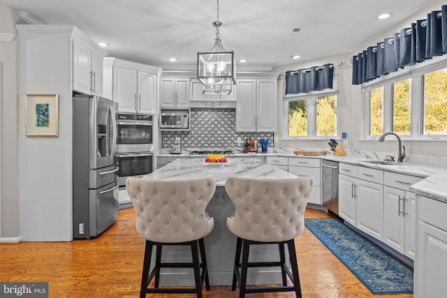 kitchen featuring backsplash, stainless steel appliances, sink, white cabinetry, and a kitchen island