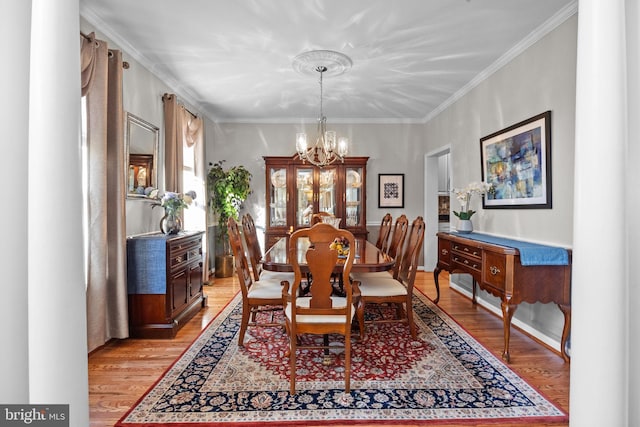 dining area featuring light hardwood / wood-style flooring, a notable chandelier, and crown molding