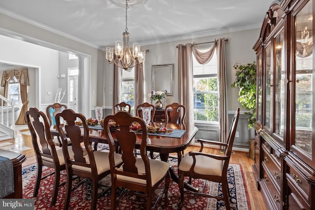 dining room with decorative columns, an inviting chandelier, ornamental molding, and light hardwood / wood-style flooring