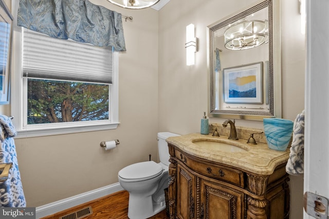 bathroom featuring vanity, toilet, wood-type flooring, and a chandelier