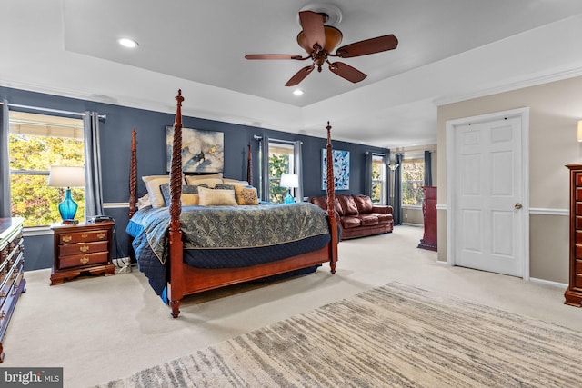 carpeted bedroom featuring multiple windows, a tray ceiling, and ceiling fan