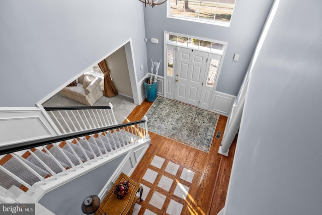 foyer entrance with a chandelier, a towering ceiling, and light wood-type flooring