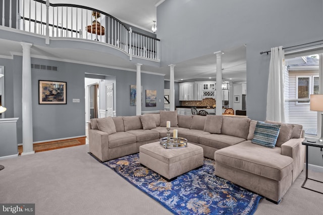 living room with carpet, ornate columns, crown molding, and a high ceiling