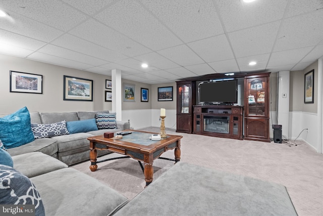 living room featuring carpet and a paneled ceiling