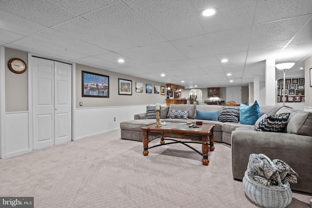 carpeted living room featuring a drop ceiling