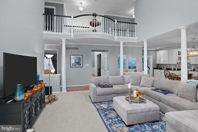 living room with decorative columns, a towering ceiling, crown molding, and carpet floors