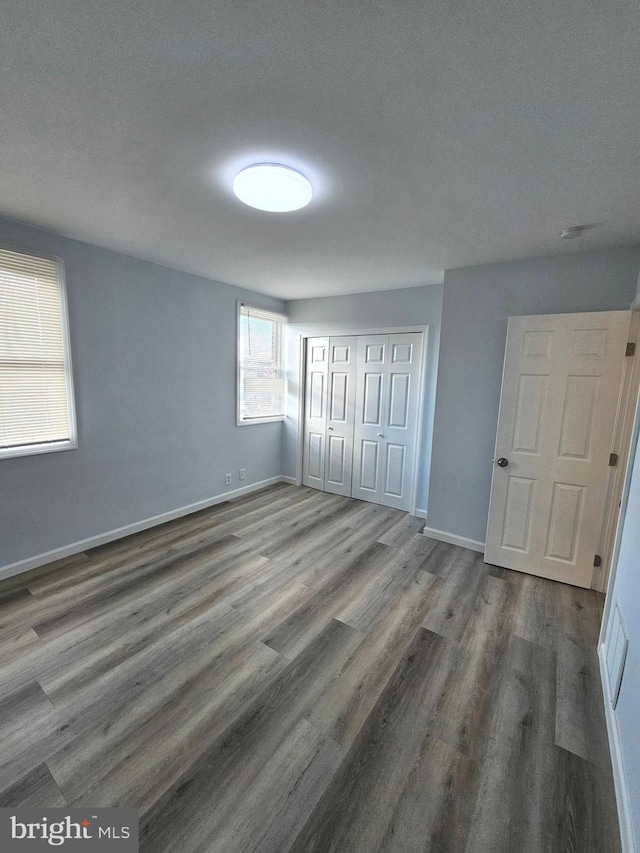 unfurnished bedroom featuring dark hardwood / wood-style floors, a textured ceiling, and a closet