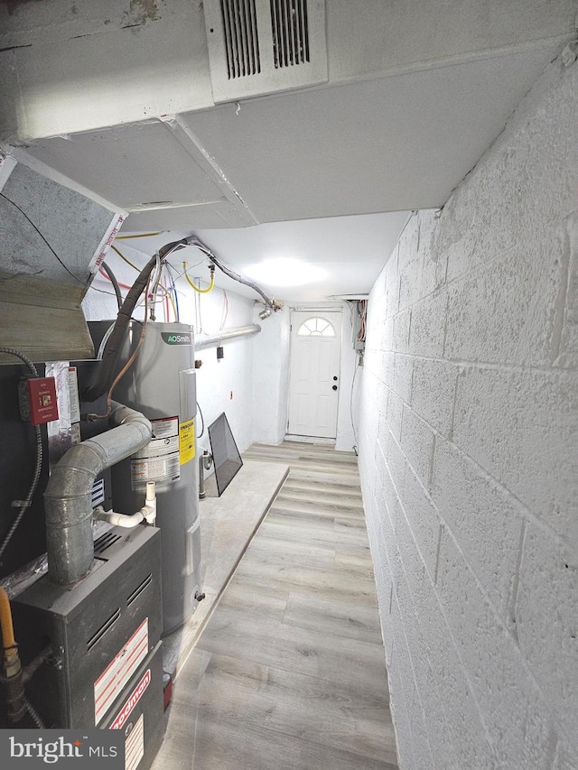 basement with electric water heater and light hardwood / wood-style flooring