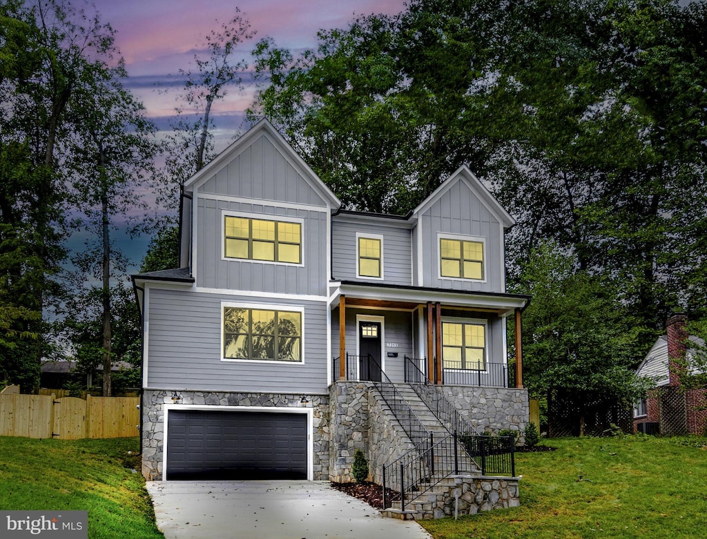 view of front of property with covered porch, a garage, and a lawn