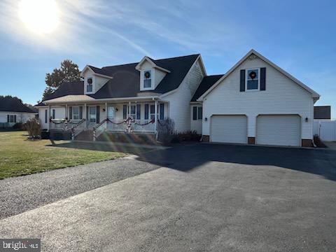 view of front of property featuring a porch, a garage, and a front lawn